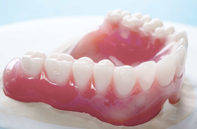 Dental model showing teeth arrangement on pink gum base for orthodontic or prosthodontic education.