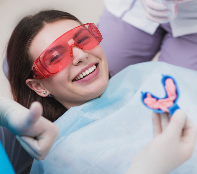Young patient wearing protective red glasses smiles during dental examination at Marion DDS office.