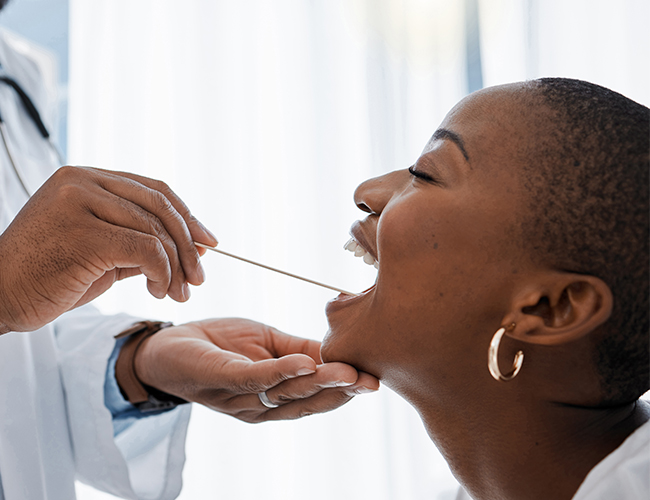 Healthcare provider performing throat examination on patient during medical visit.