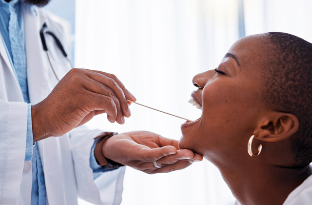 Healthcare provider performing throat examination on patient in medical office setting.