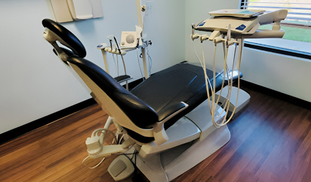 Dental examination chair with overhead light and instruments in modern dentist office.