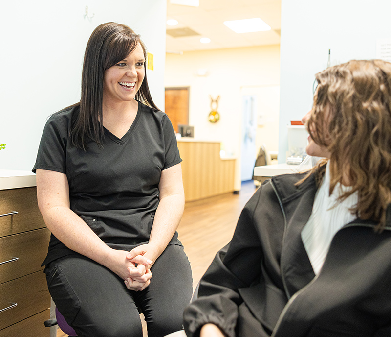 Two women having a conversation in a dental office waiting area.