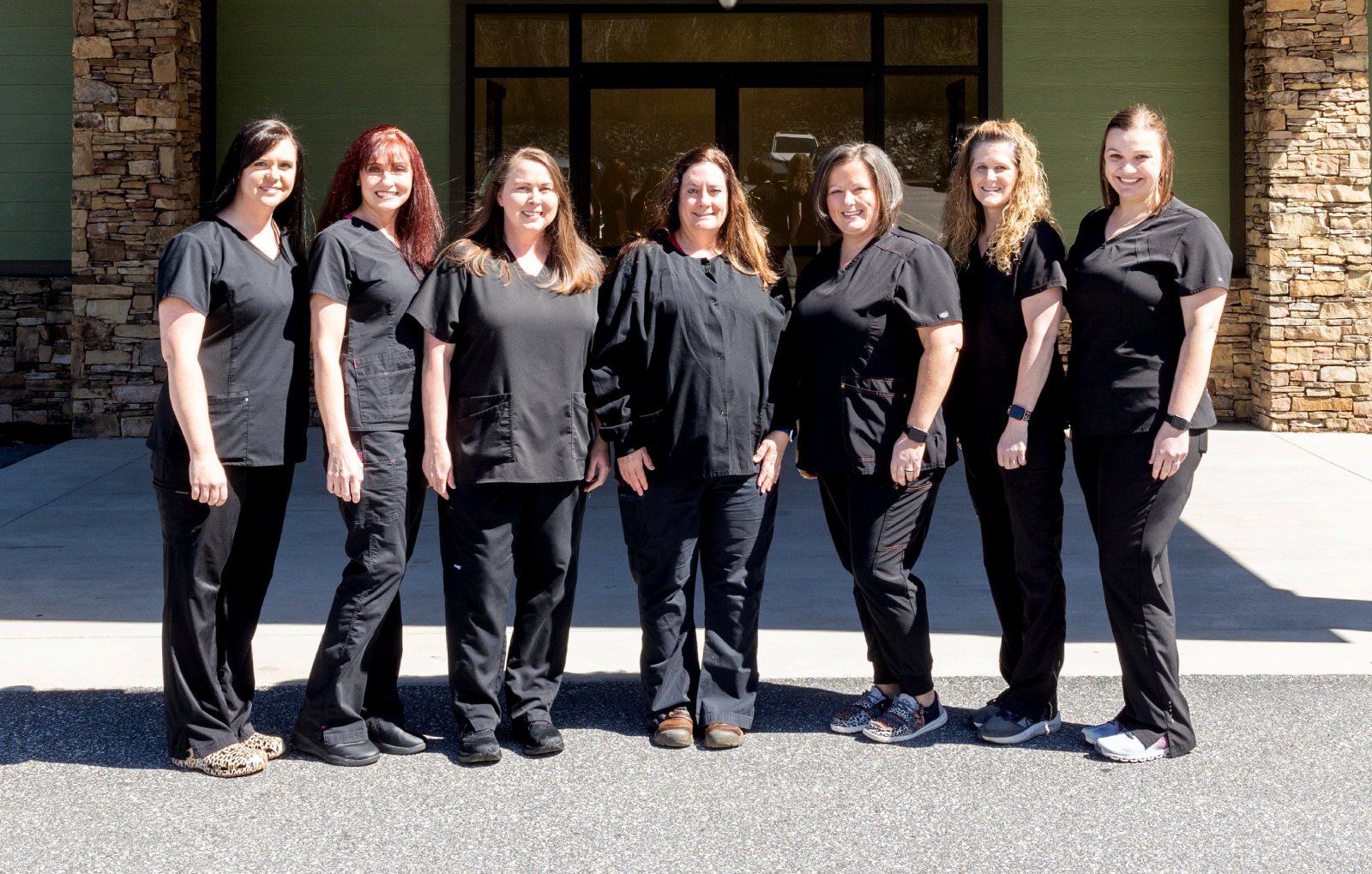 Team of dental professionals in matching black scrubs standing together outdoors at Marion DDS clinic.