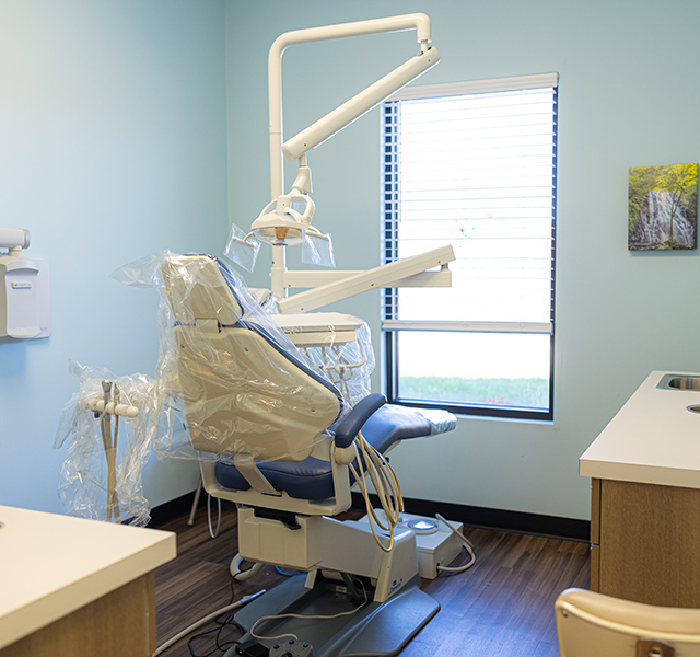 Modern dental operatory with chair, overhead light, and equipment in bright clinical setting.